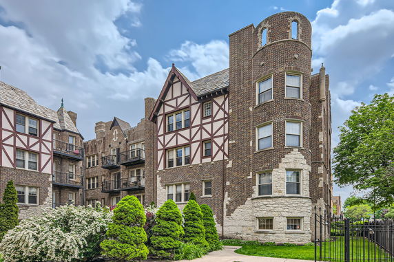 Front view of a multi-story brick apartment building with Tudor-style elements.