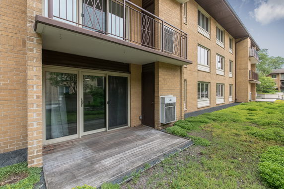 Front view of a multi-story brick building with balconies and a patio area.