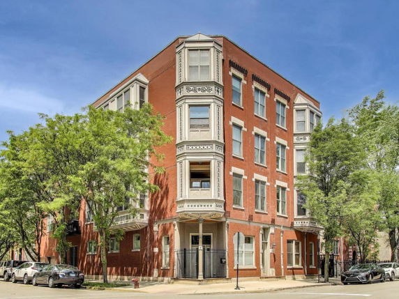 Front view of a multi-story brick building on a street corner.