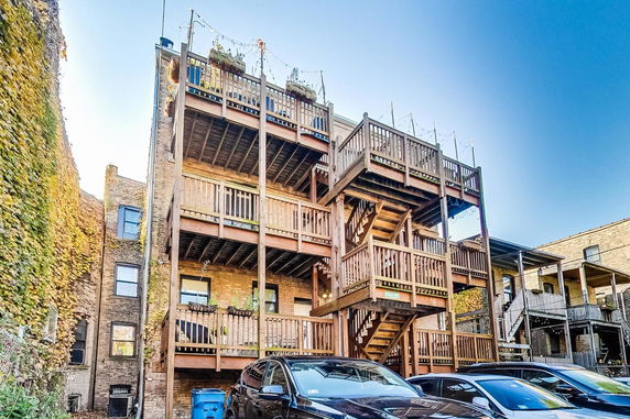 Rear view of a multi-story building with wooden balconies and staircases.