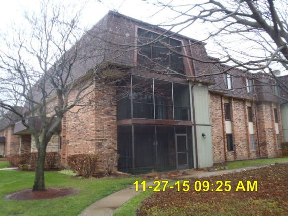 Front view of a multi-story brick building with enclosed balconies.