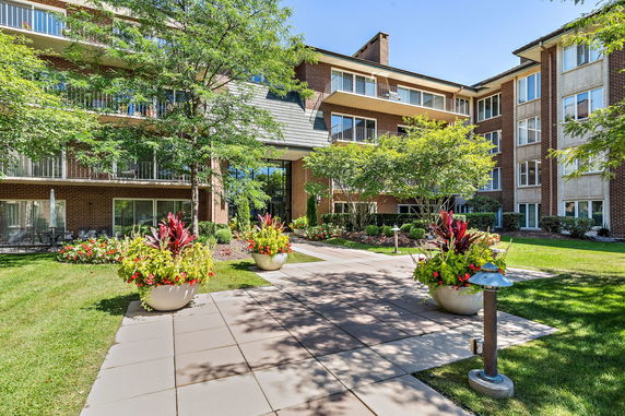 Front view of a multi-story building with balconies and garden area.