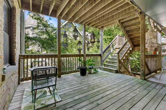 Wooden rooftop deck with stairs and hanging lights.