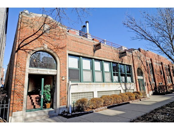 Front view of a brick building with large arched windows and doors.