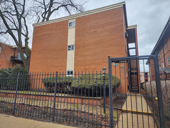 Front view of a multi-story building with brick exterior and stairway entrance.