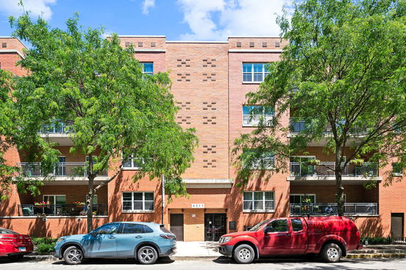Front view of a multi-story brick apartment building with balconies.
