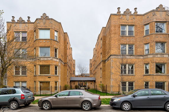 Front view of a multi-story brick apartment building with bay windows.