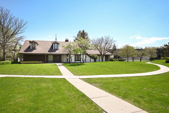 Front view of a single-story house with a brown roof and dormer windows.