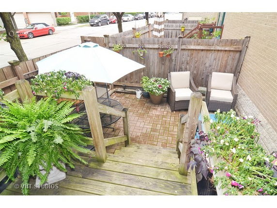 Outdoor patio area with seating and an umbrella, surrounded by a wooden fence.