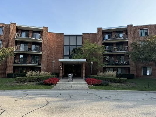 Front view of a multi-story apartment building with red brick facade and balconies.