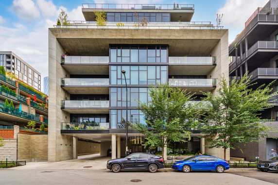Front view of a modern multi-story building with glass balconies and a concrete facade.