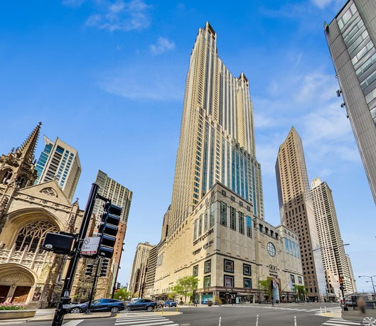 Front view of a tall skyscraper building with a large shopping base.