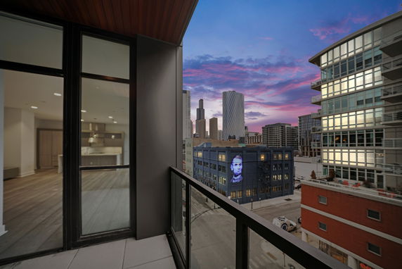 View from a balcony showing cityscape with modern buildings at sunset.