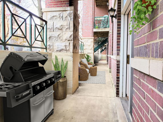 Outdoor walkway with a grill and seating area in a building complex.