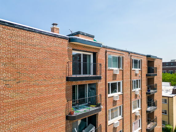Front view of a multi-story brick apartment building with balconies.