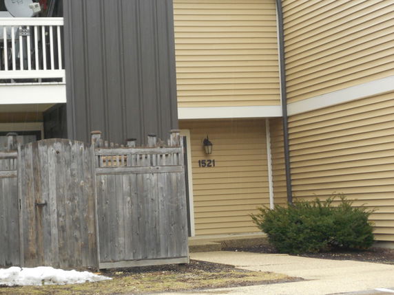 Front view of a house with beige siding and wooden fencing.