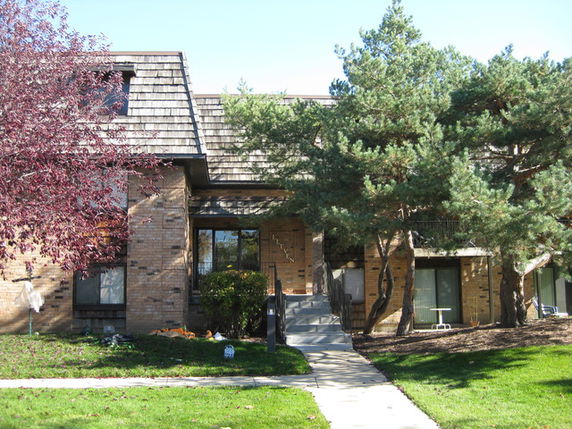 Front view of a two-story house with brick exterior and overhanging roof.