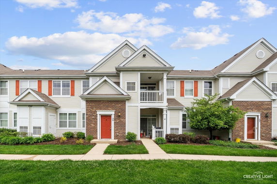 Front view of a two-story residential building with multiple entrances and red doors.