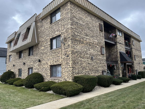 Front view of a three-story brick residential building with balconies.