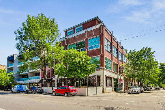 Front view of a multi-story brick building on a street corner.