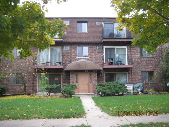 Front view of a three-story brick building with balconies.