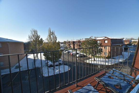 View from a balcony overlooking residential buildings and a parking area.