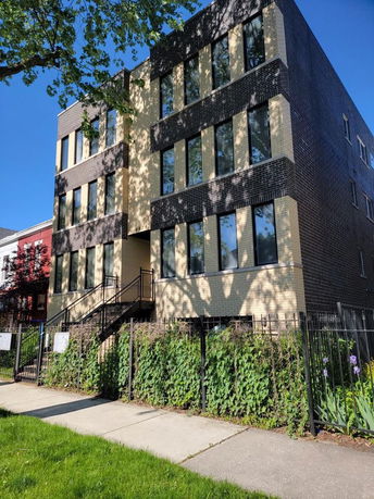 Front view of a multi-story building with large windows and brick facade.