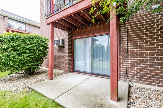 Elevated view of a brick building with sliding glass doors and a balcony above.