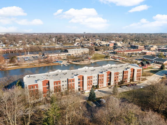Panoramic view of a cityscape with a large building complex near a river and surrounding areas.