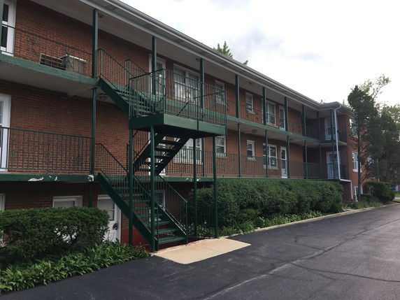 Front view of a two-story brick apartment building with external staircases.