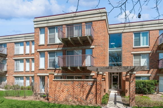 Front view of a three-story brick apartment building with balconies.