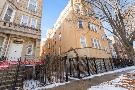 Front view of a multi-story brick apartment building with decorative fencing.