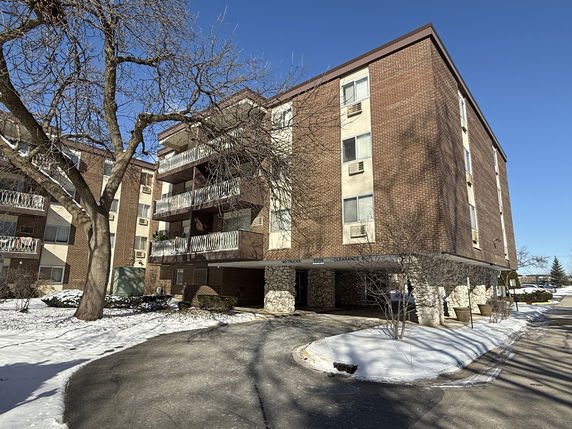 Front view of a multi-story brick apartment building with balconies.