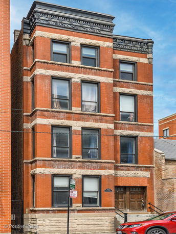 Front view of a multi-story brick building with decorative elements on top.