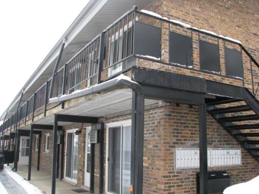 Front view of a two-story brick building with exterior staircases and balconies.