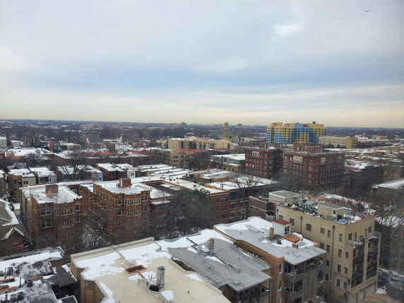 Panoramic view of a snowy urban landscape with buildings and a cloudy sky.