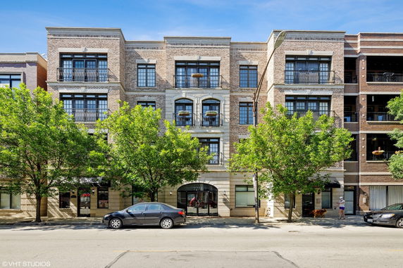 Front view of a multi-story brick building with balconies and large windows.