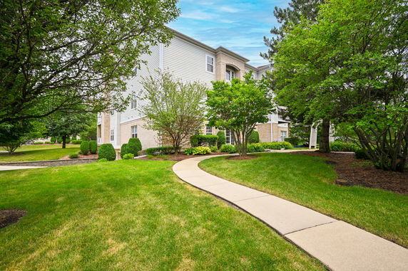 Front view of a multi-story residential building with a landscaped pathway.