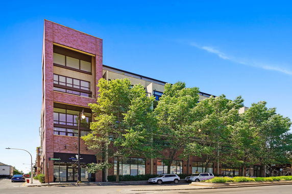 Front view of a multi-story building with large windows and a brick facade.