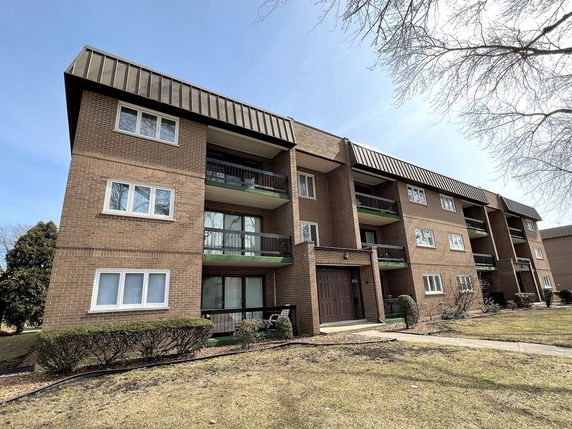 Front view of a multi-story brick apartment building with balconies.