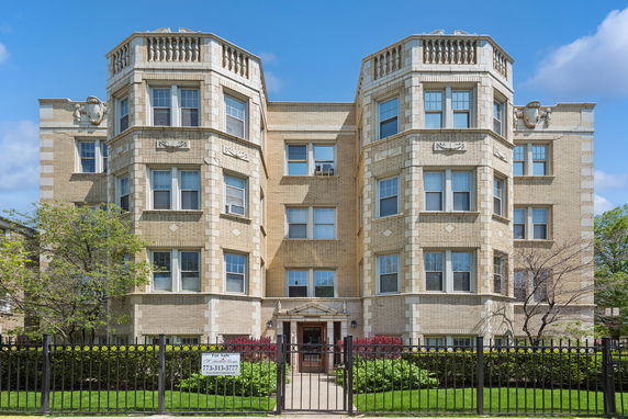 Front view of a multi-story apartment building with decorative elements and bay windows.