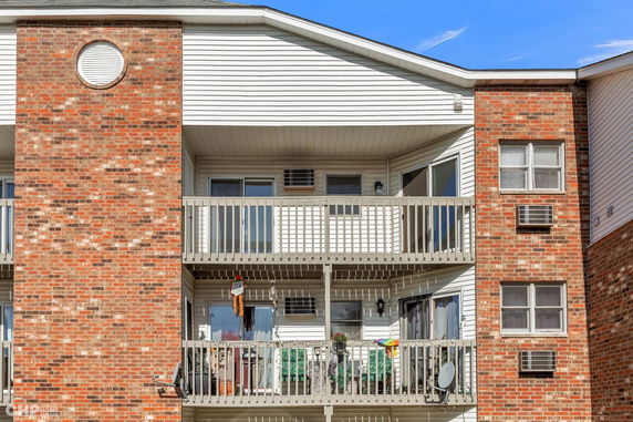 Front view of a multi-story building with balconies and brick facade.