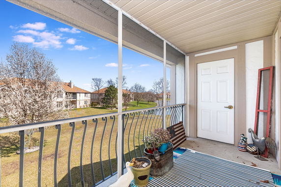 Balcony view with railing overlooking trees and buildings.