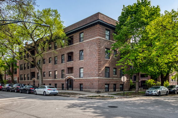 Front view of a three-story brick apartment building on a corner street.
