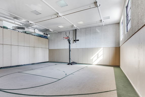 Indoor basketball court with high ceiling and wall padding.