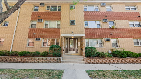 Front view of a multi-story apartment building with brick facade and multiple windows.