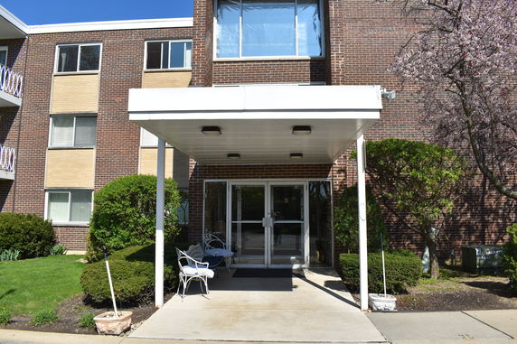 Front view of a brick apartment building with a covered entrance.