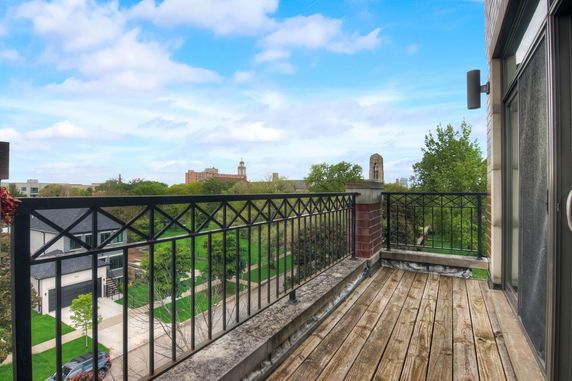 Balcony view showing surrounding buildings and greenery.