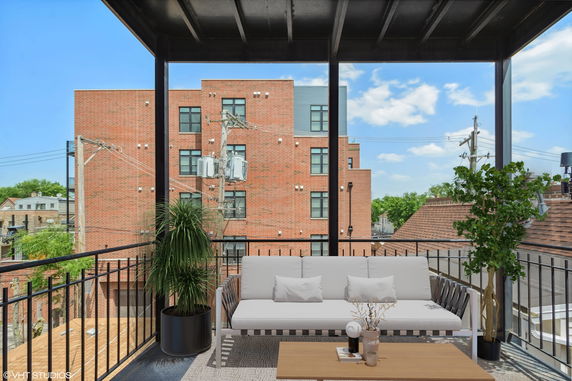 View from a covered balcony showing a nearby brick building and clear sky.