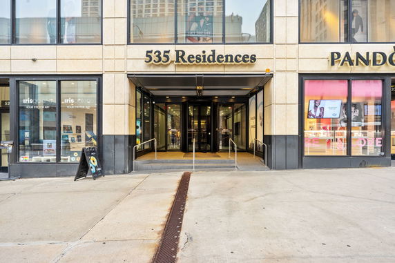 Front view of a building with signage for 535 Residences and storefronts on either side.